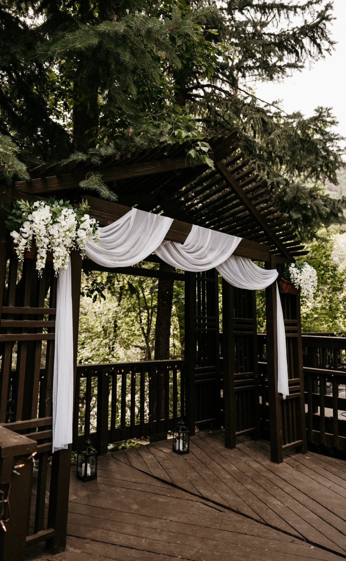 Wooden gazebo decorated with white fabric and flowers for an intimate wedding ceremony