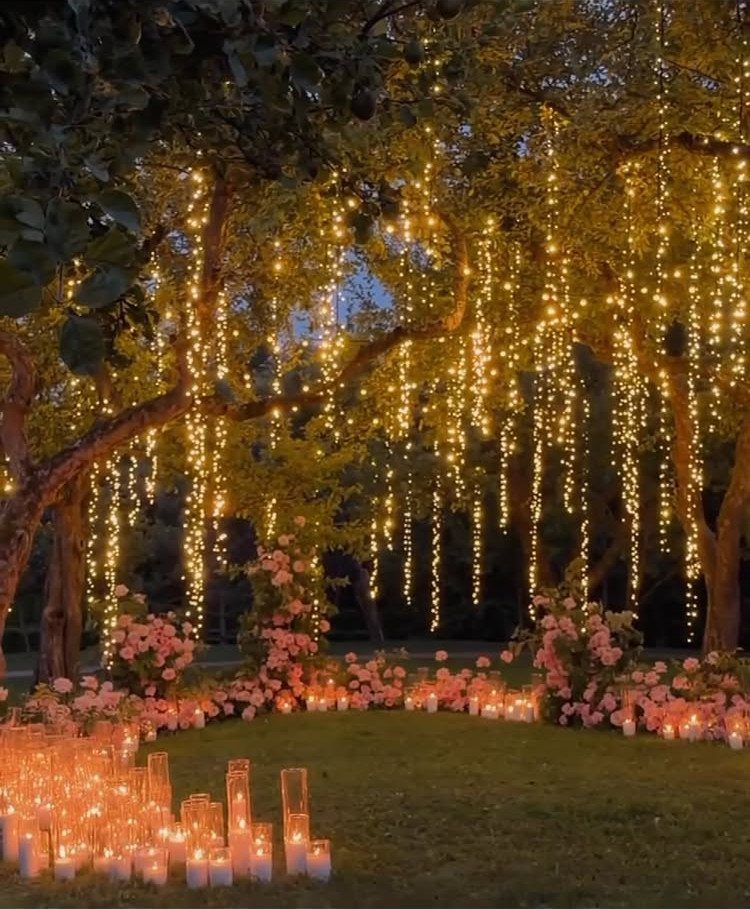 Hanging string lights and pillar candles illuminating a romantic outdoor garden wedding setting