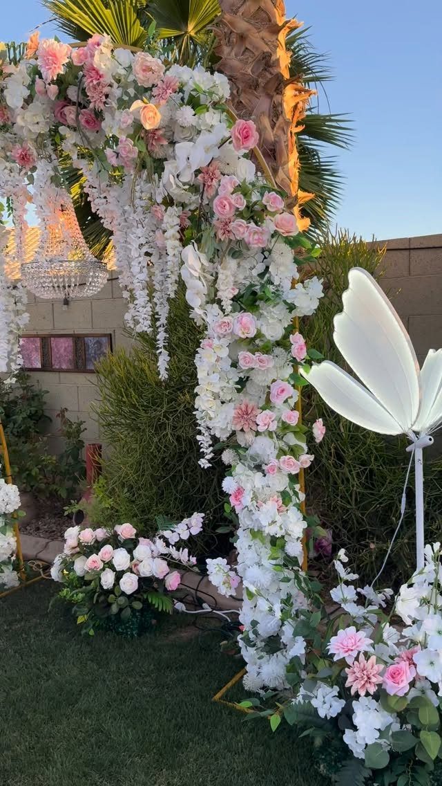 Floral wedding arch with pink and white roses and a crystal chandelier in backyard