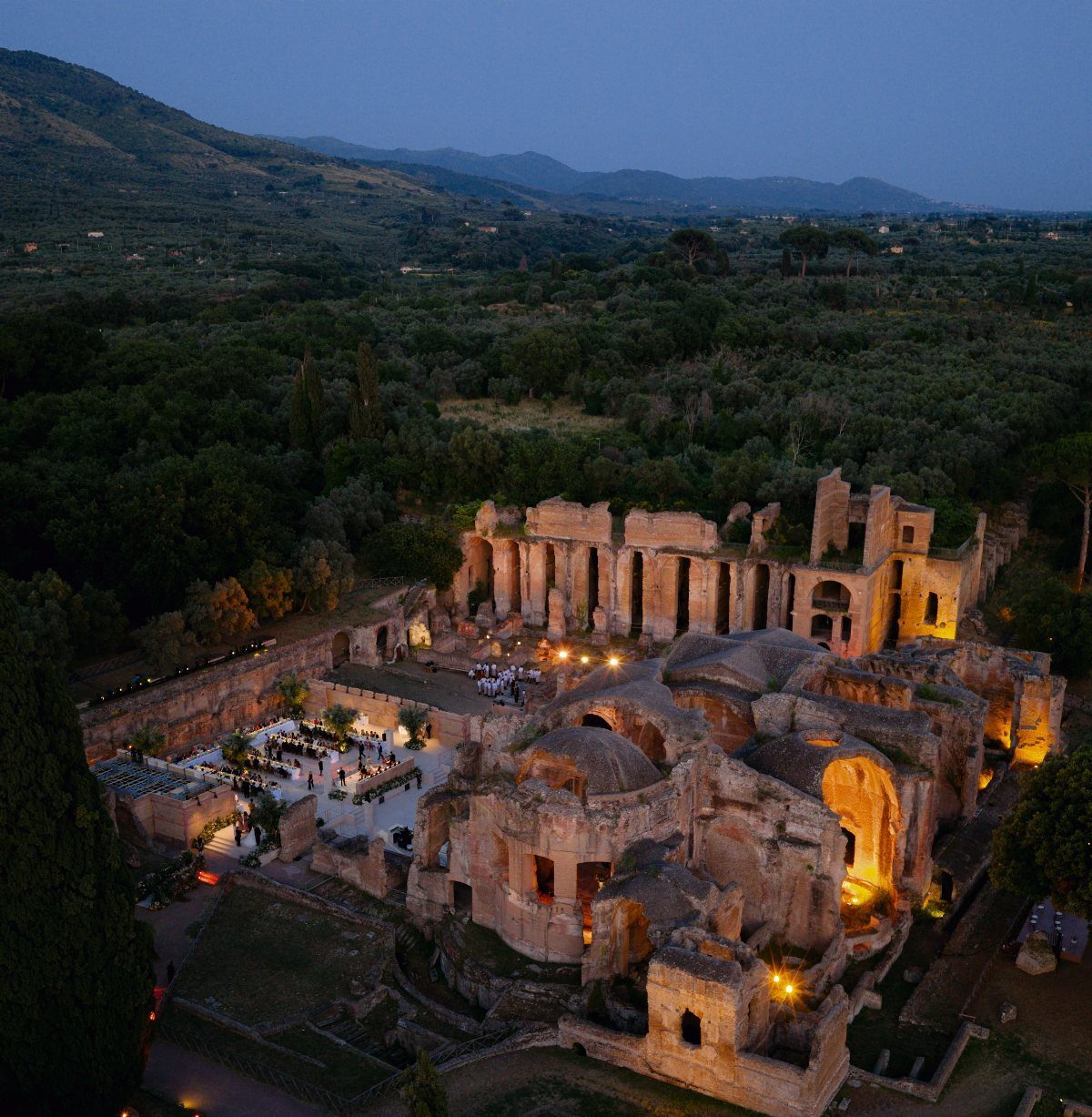Ancient stone ruins illuminated at night hosting a wedding reception in a forest