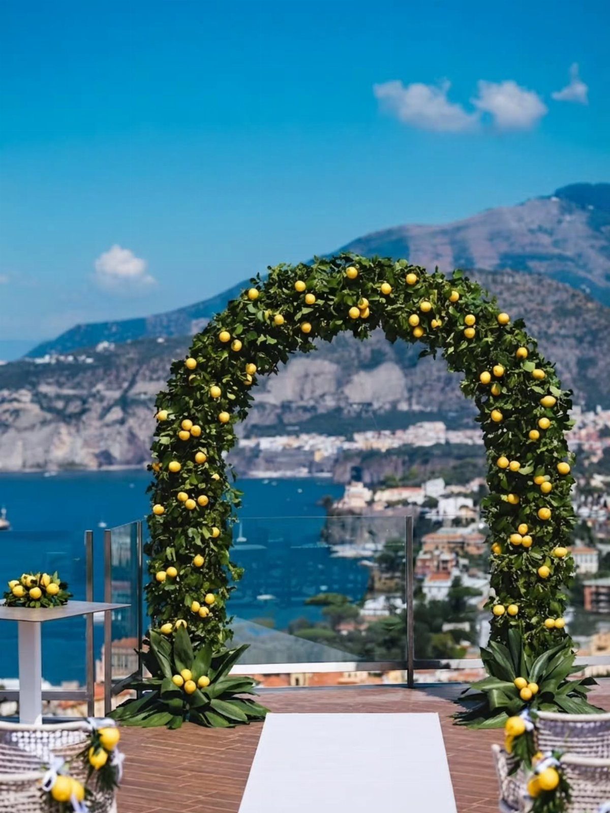 Lemon-decorated wedding arch overlooking a scenic Italian coastal town and blue sea.