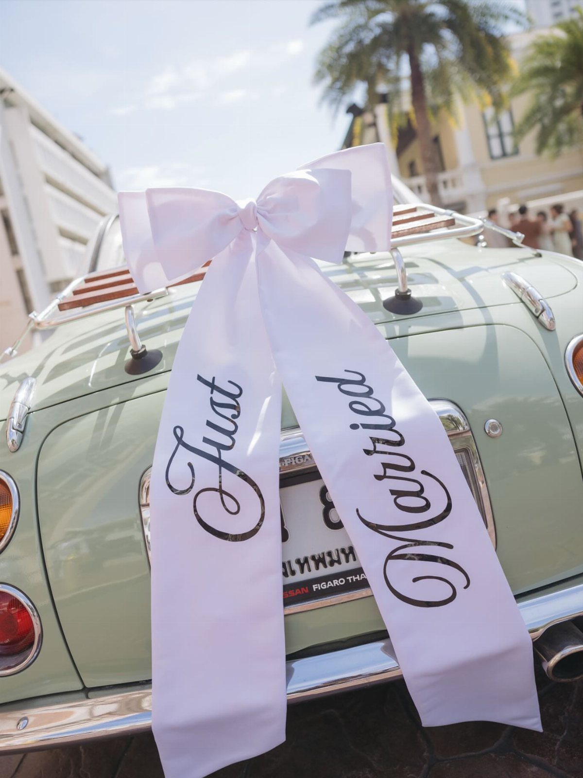 White Just Married ribbon and bow tied to a light green vintage car