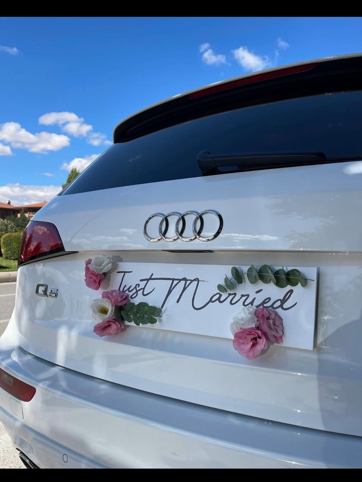 White Audi SUV with a Just Married sign decorated with pink roses.