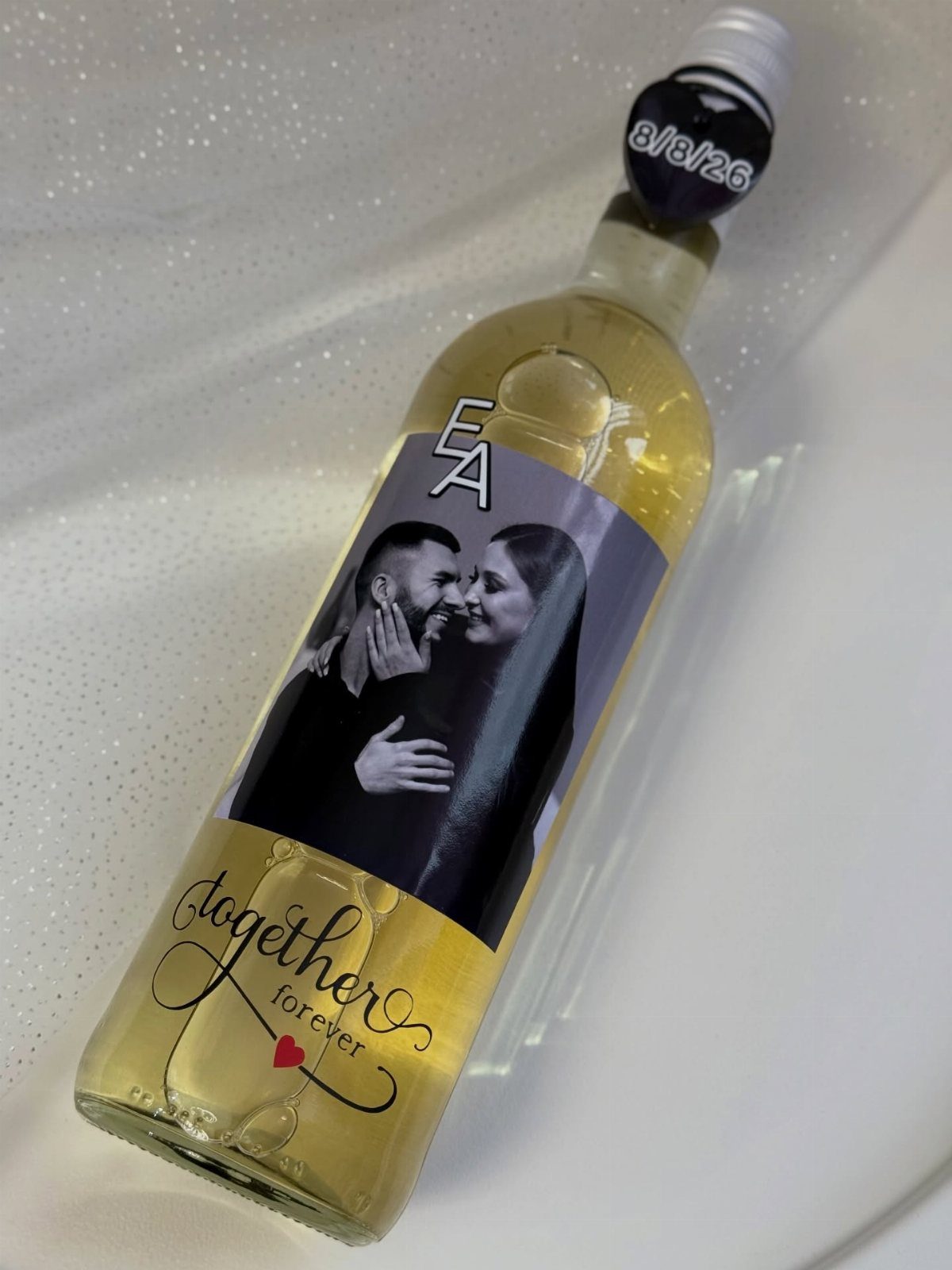 Bottle of yellow liquid with a personalized label showing a couple and text.