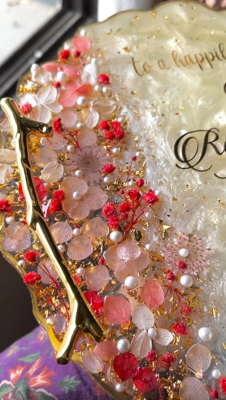 Resin tray with embedded pink dried flowers, white pearls, and gold leaf accents.