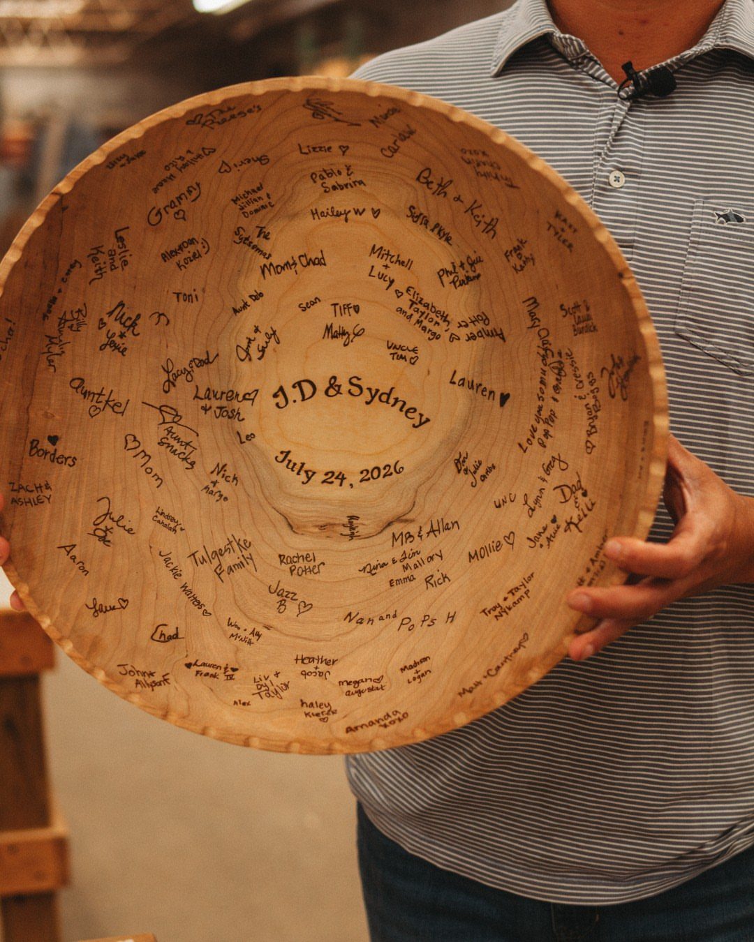 Large wooden bowl with handwritten wedding guest signatures and names of the couple.