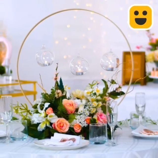 Floral centerpiece with pink roses inside a gold hoop with hanging glass candles