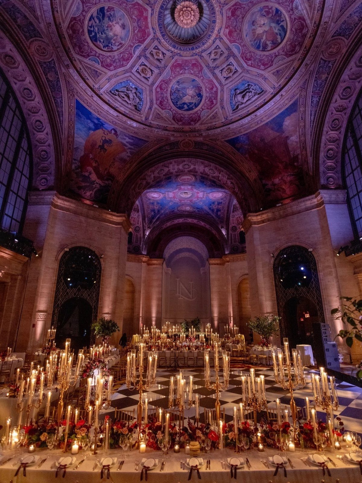 Grand hall with painted vaulted ceilings and tables set with gold candelabras.