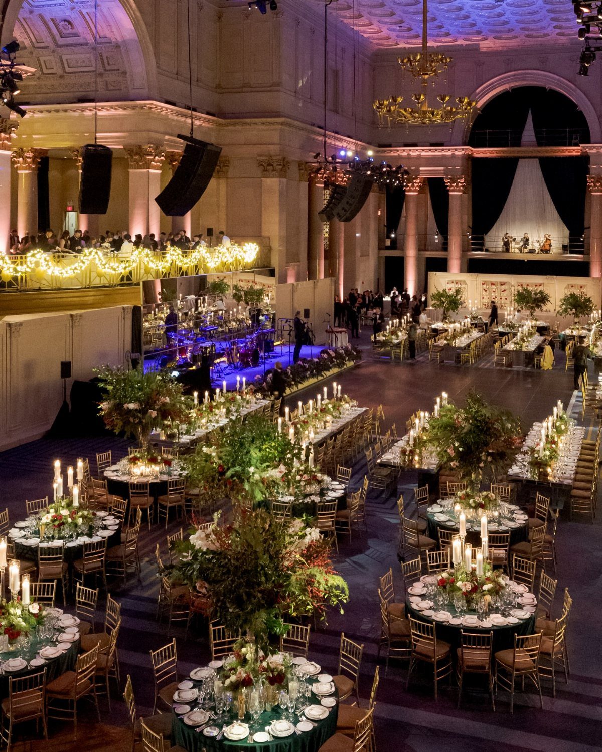 Grand wedding reception hall with ornate architecture, candlelit tables, and lush floral arrangements.