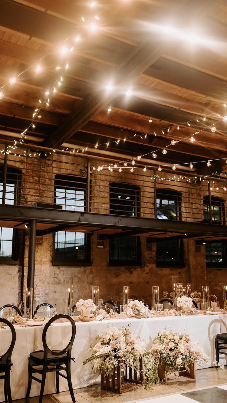 Wedding reception table with white linens and flowers in an industrial brick venue