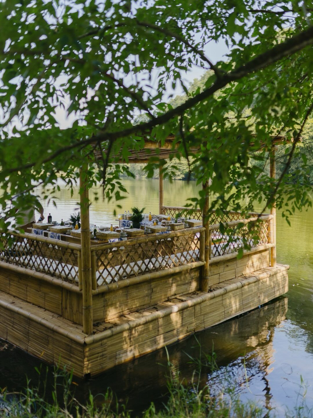 Bamboo floating dining platform on a lake surrounded by lush green trees