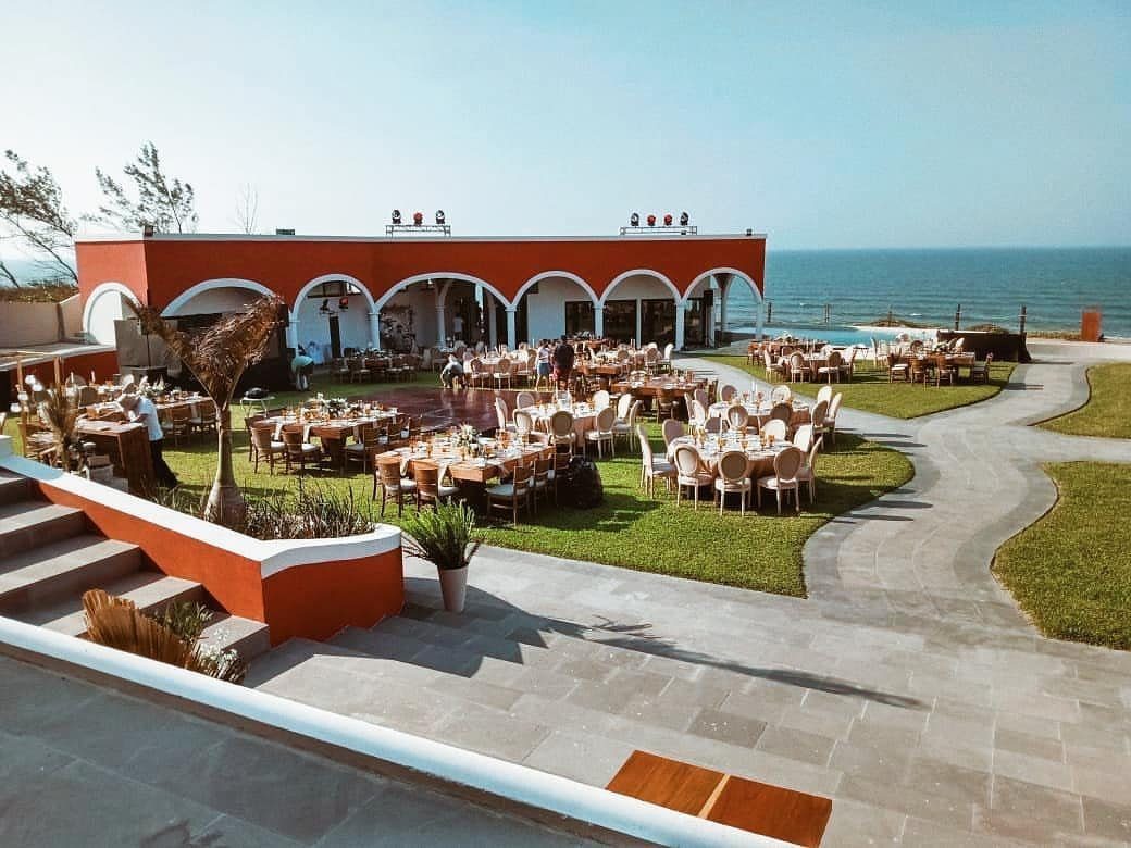 Outdoor wedding reception with round tables on a lawn overlooking the ocean.