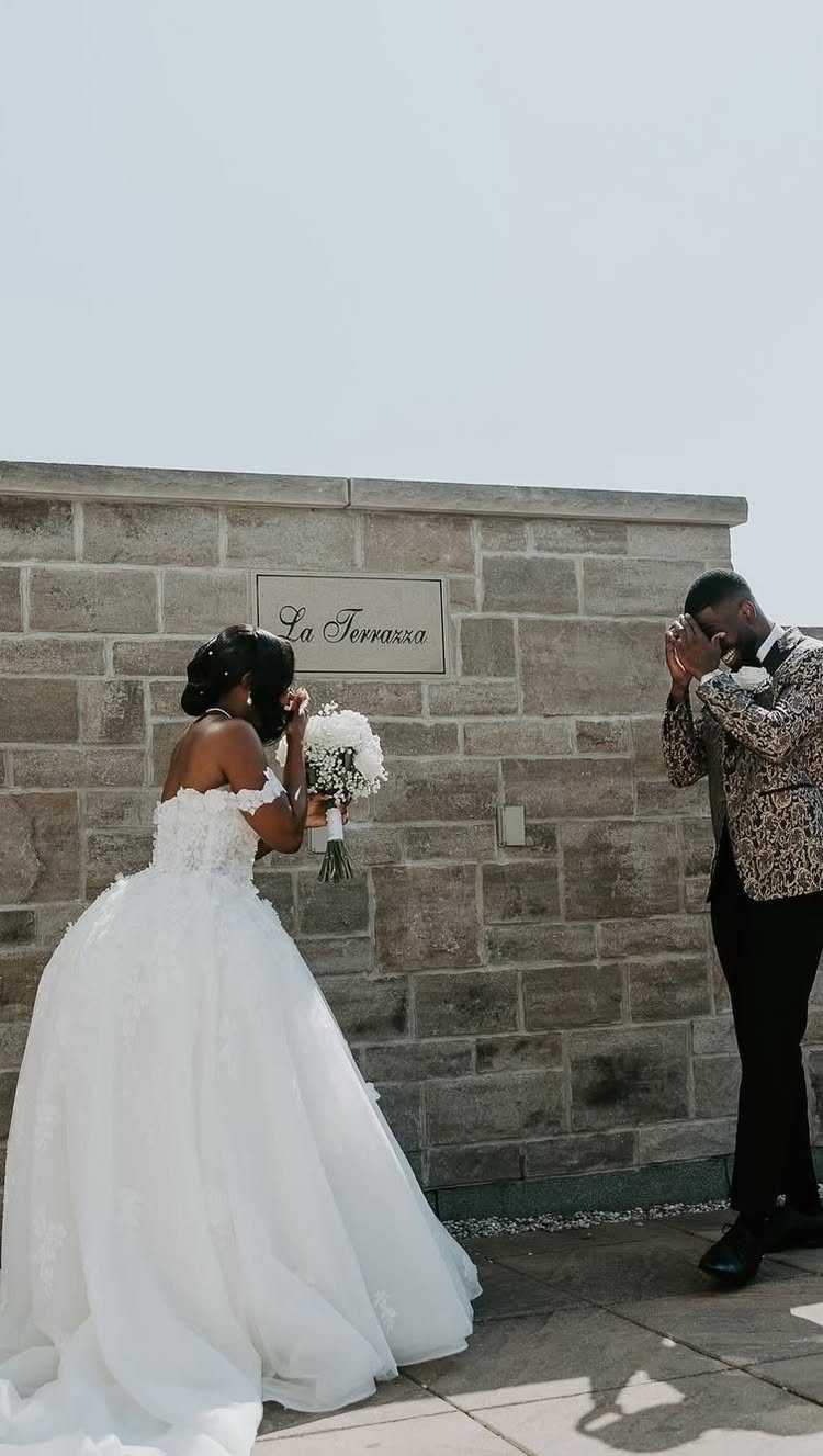 Bride and groom sharing a first look moment against a stone wall outdoors.