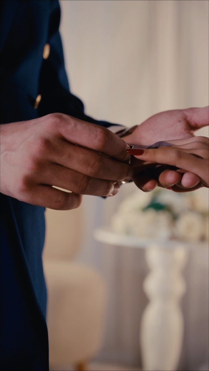 Groom in navy suit placing a wedding ring on the bride's finger