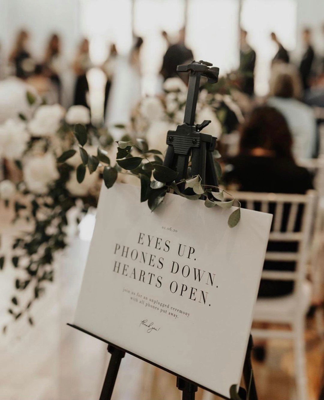 Unplugged ceremony sign with floral greenery at a modern wedding ceremony venue