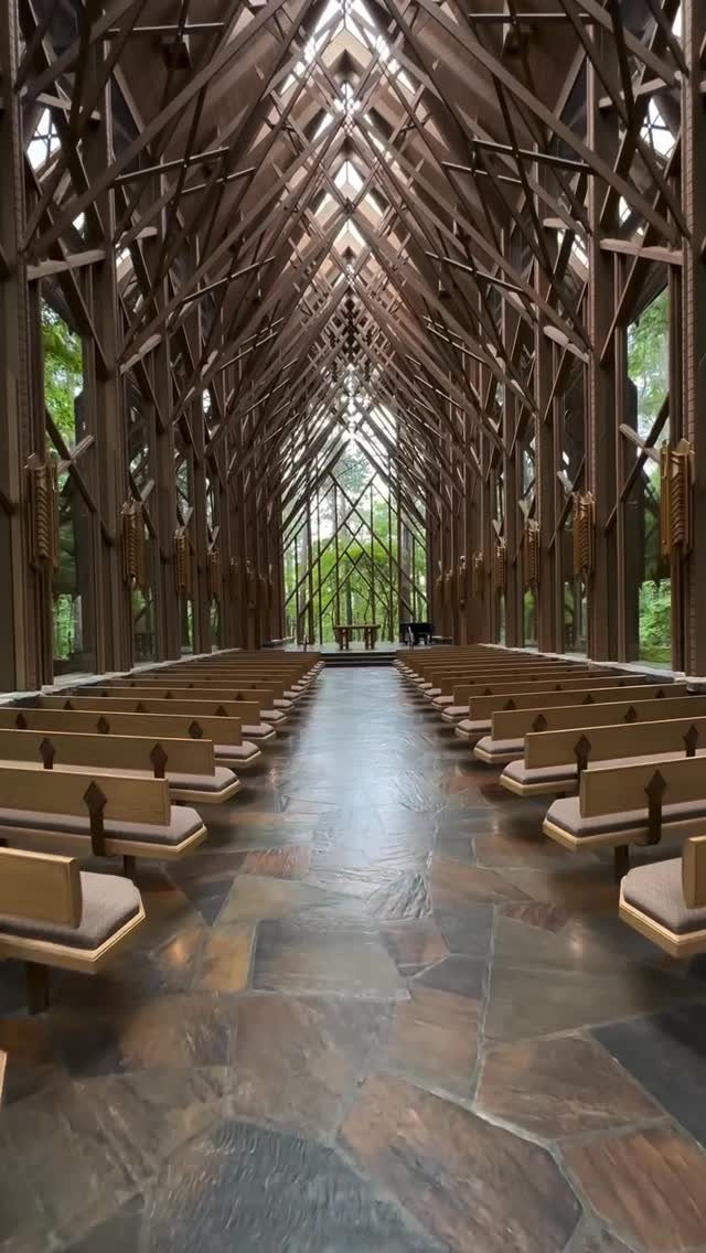 Chapel interior with intricate wooden ceiling beams and expansive glass walls overlooking nature.