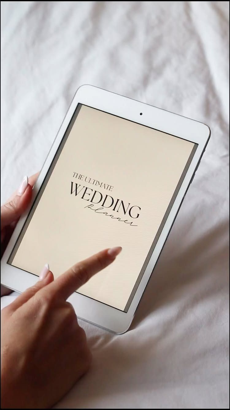 Hand pointing to a digital wedding planner displayed on a white tablet screen