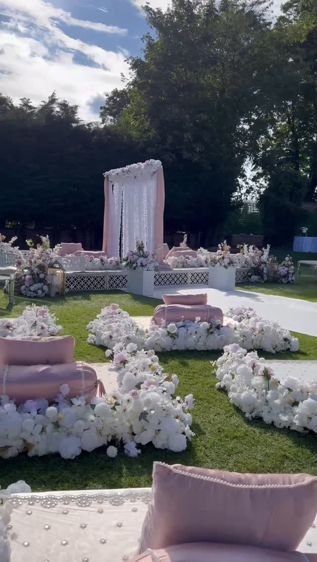 Pink floor cushions and white flowers as seating for an outdoor wedding ceremony.