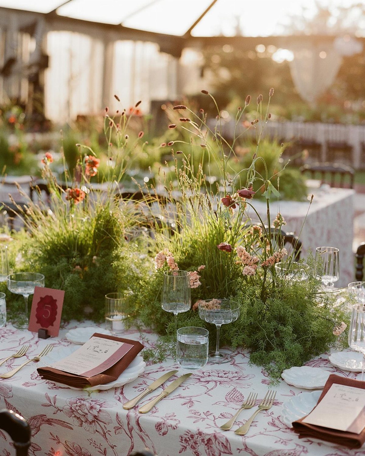 Wild floral centerpieces on a patterned tablecloth at an outdoor wedding reception table