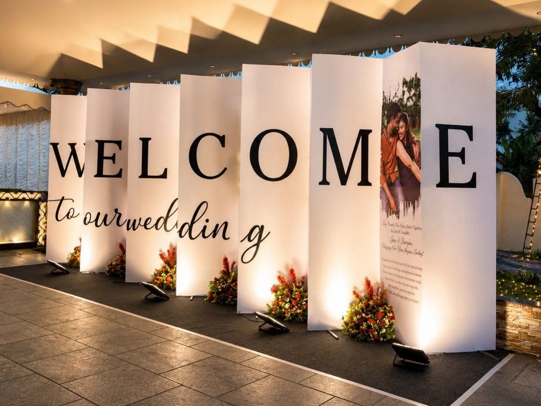 White vertical panel welcome sign for a wedding with floral accents and spotlights.