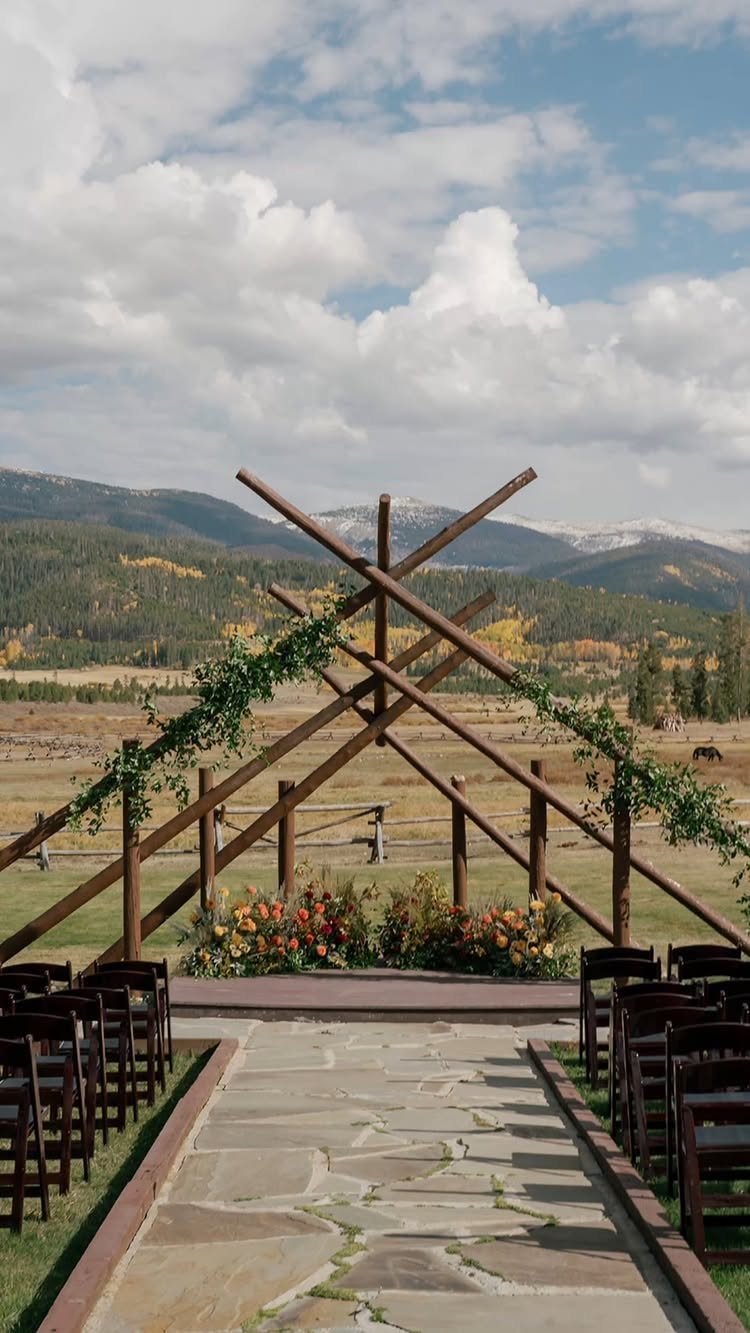 Wooden geometric wedding altar with flowers set against a mountainous wilderness landscape.