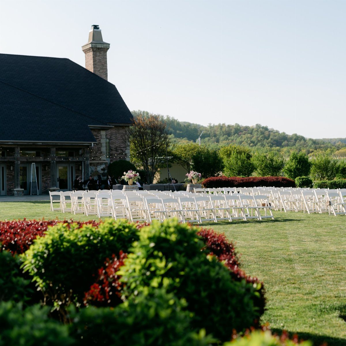 White folding chairs arranged on a green lawn for an outdoor wedding ceremony.