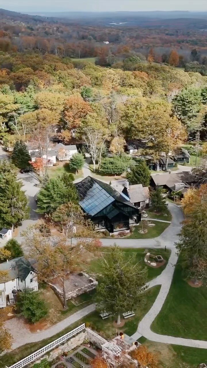 Aerial view of a rustic estate with autumn foliage and rolling hills.
