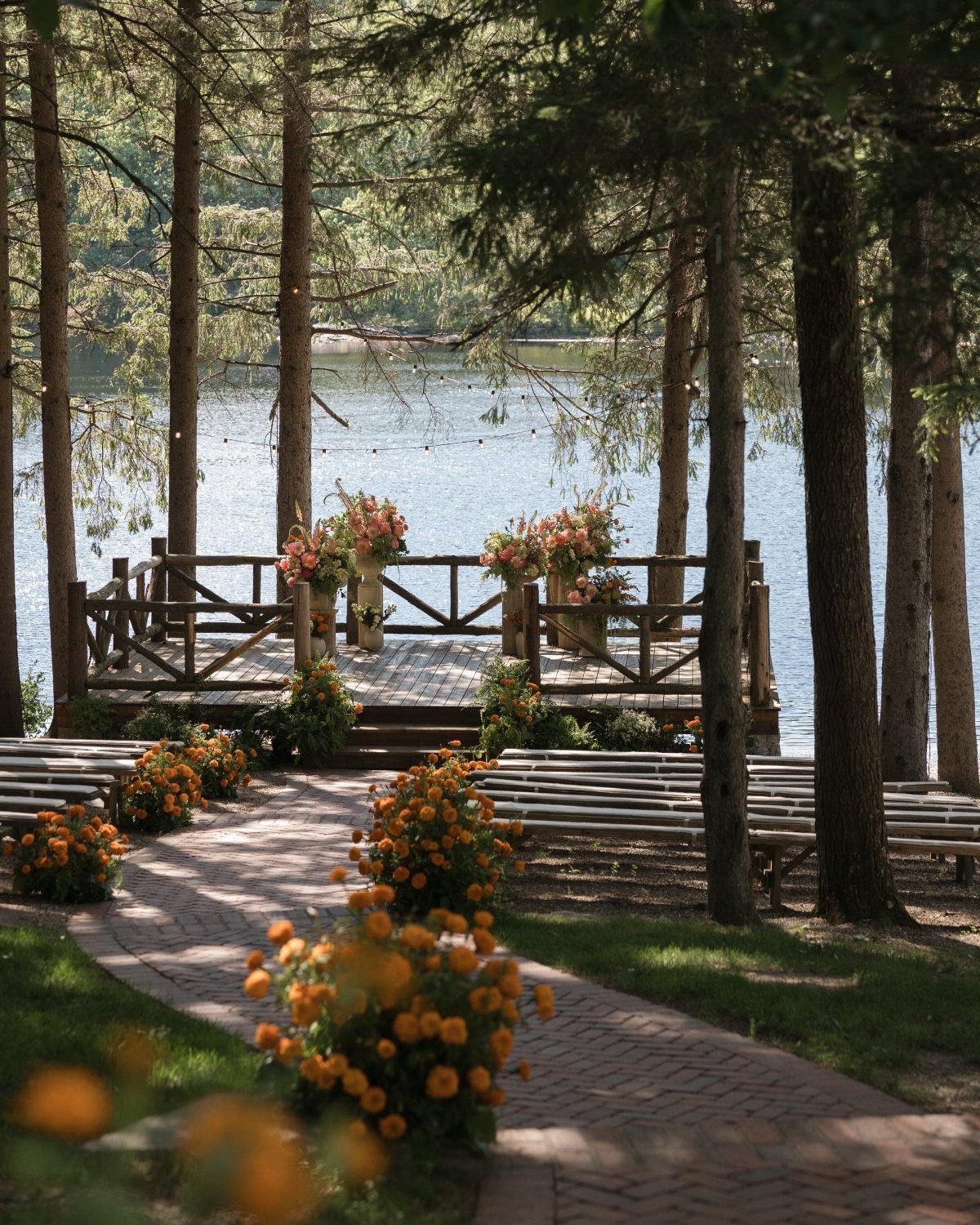 Wooden wedding altar on a deck overlooking a lake surrounded by pine trees.