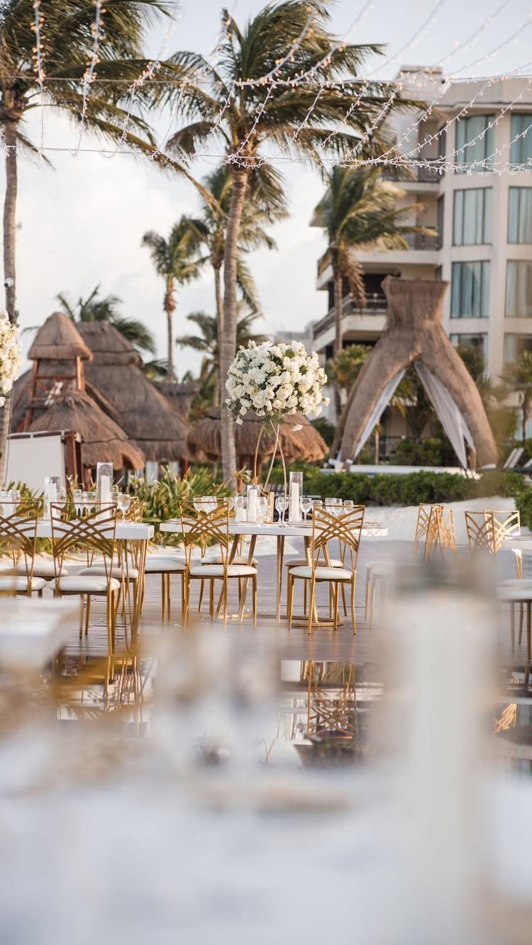 Outdoor reception tables with gold chairs and white flowers at a tropical resort.