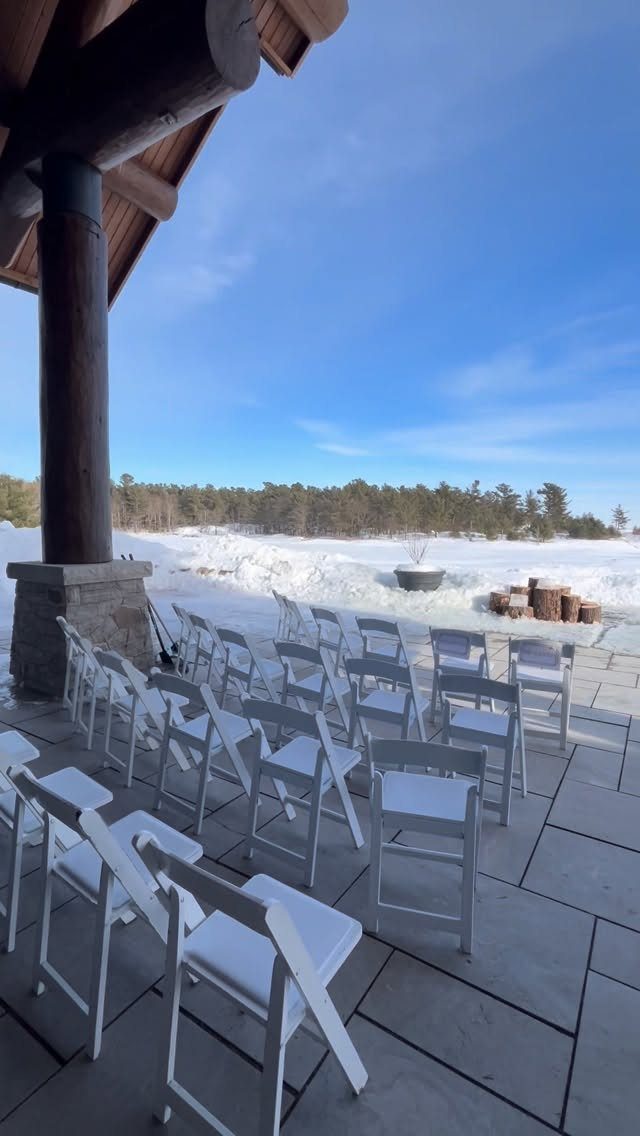 White folding chairs on a stone patio overlooking a snowy mountain landscape