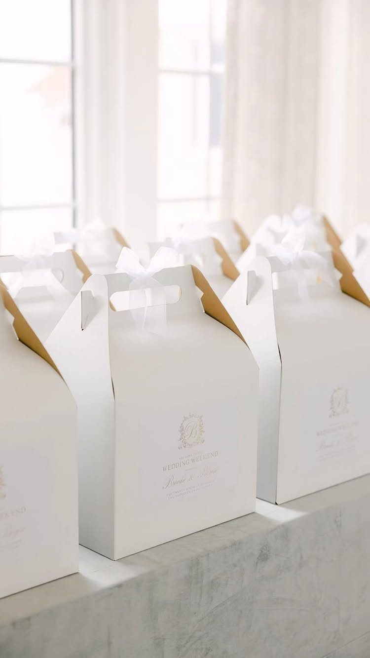 White gift boxes with gold handles and ribbons lined up on a ledge.
