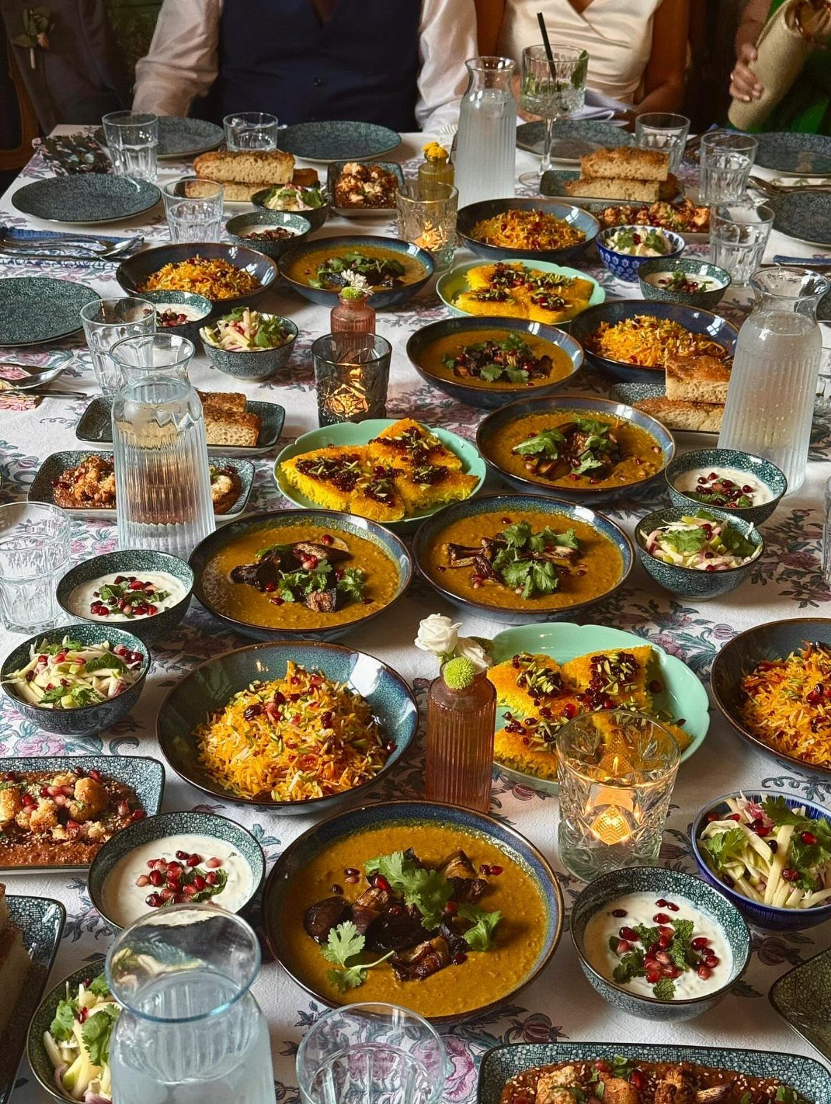 Indian feast with curries, rice, and raita served on a long dining table.