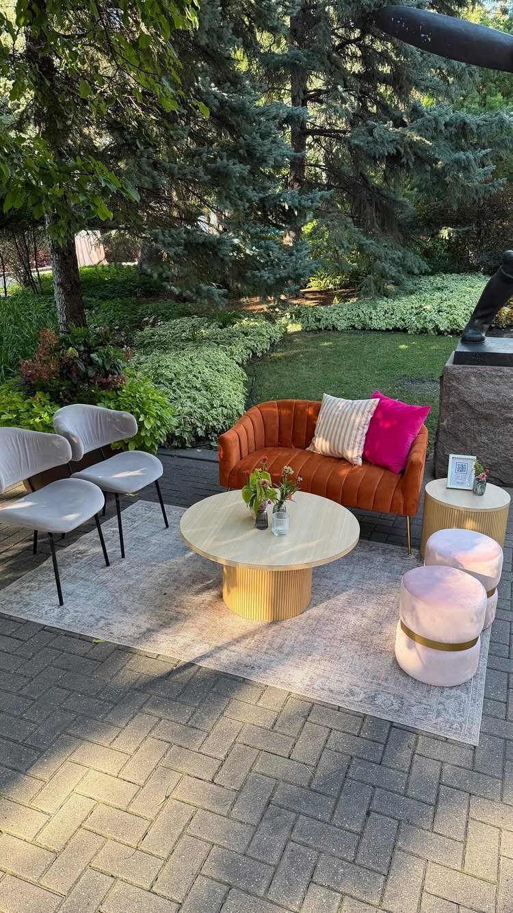 Outdoor lounge area with orange velvet sofa and pink ottomans on a patio.