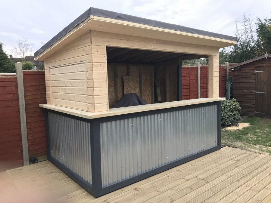 Wooden outdoor bar with corrugated metal siding on a light wood deck.