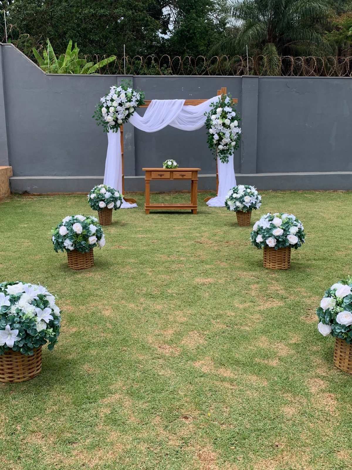 Wooden wedding arch with white fabric and flowers on a green lawn