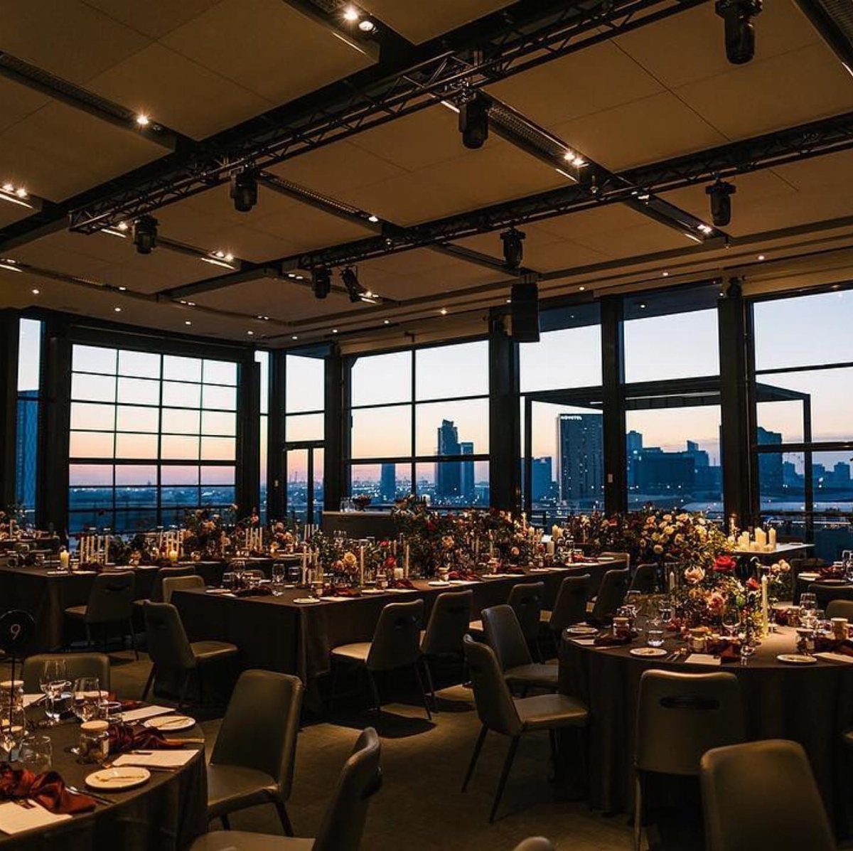 Elegant event venue with dinner tables and a city skyline view at sunset