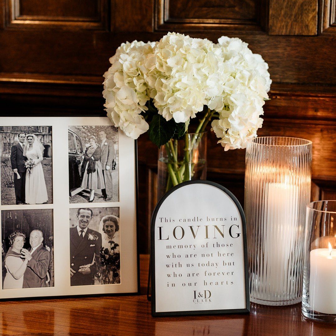 Memory table with vintage wedding photos, white hydrangeas, and lit memorial candles.