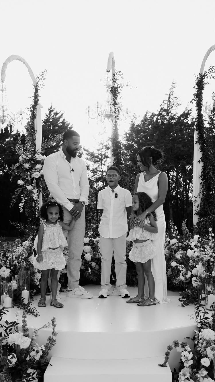 Family of five standing together on a white platform during an outdoor ceremony