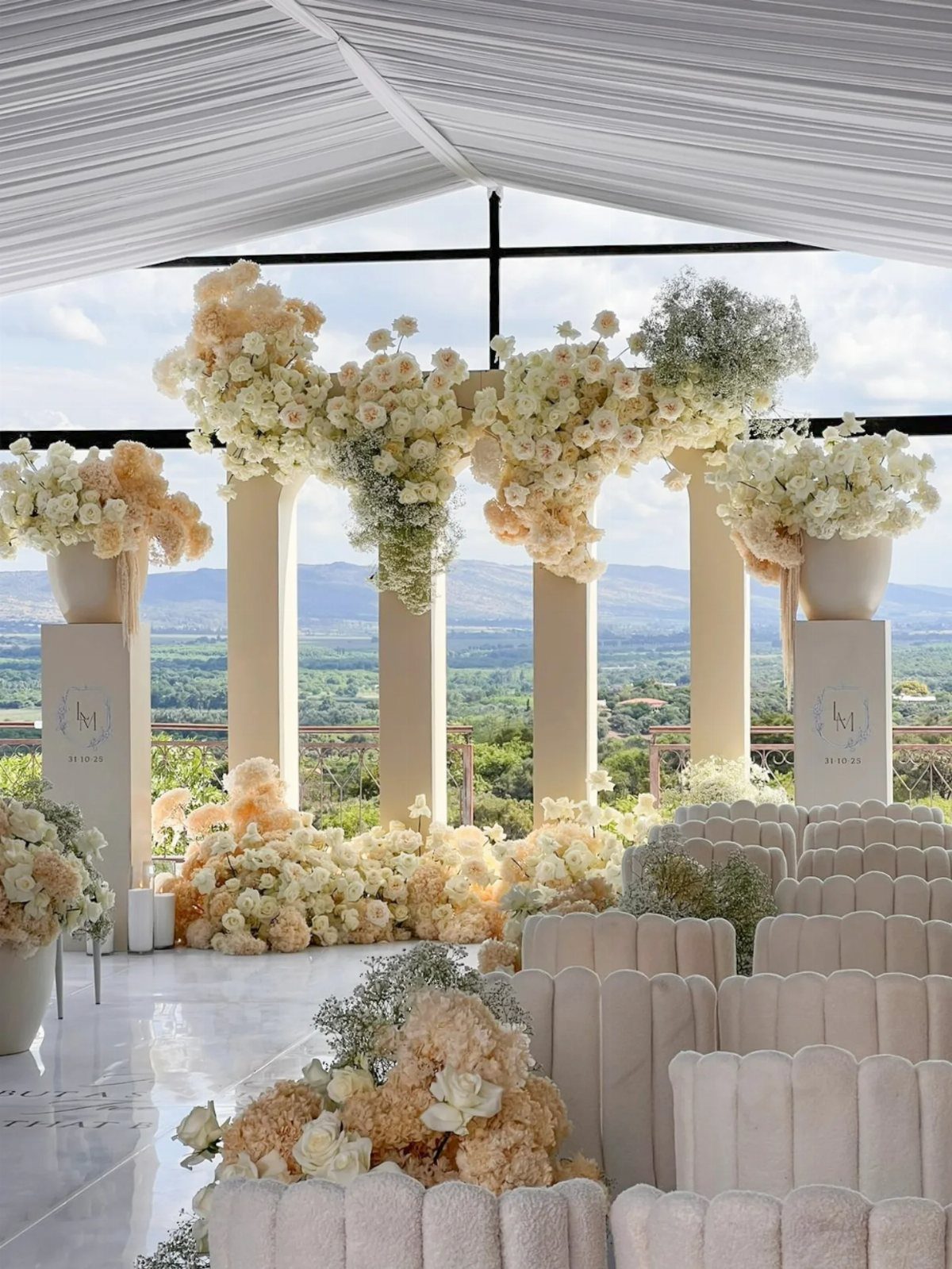 Wedding ceremony setup with white floral arrangements and chairs overlooking a mountain valley.