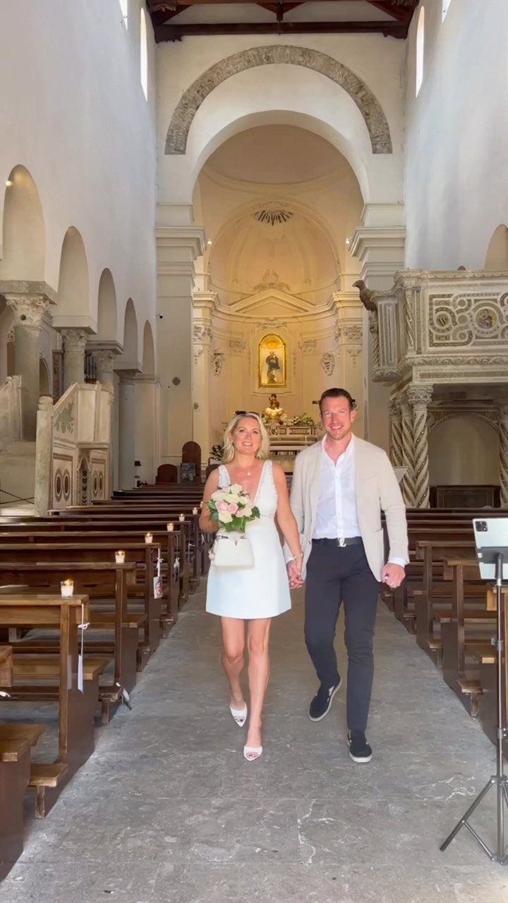 Couple walking down the aisle of a stone church after a ceremony.