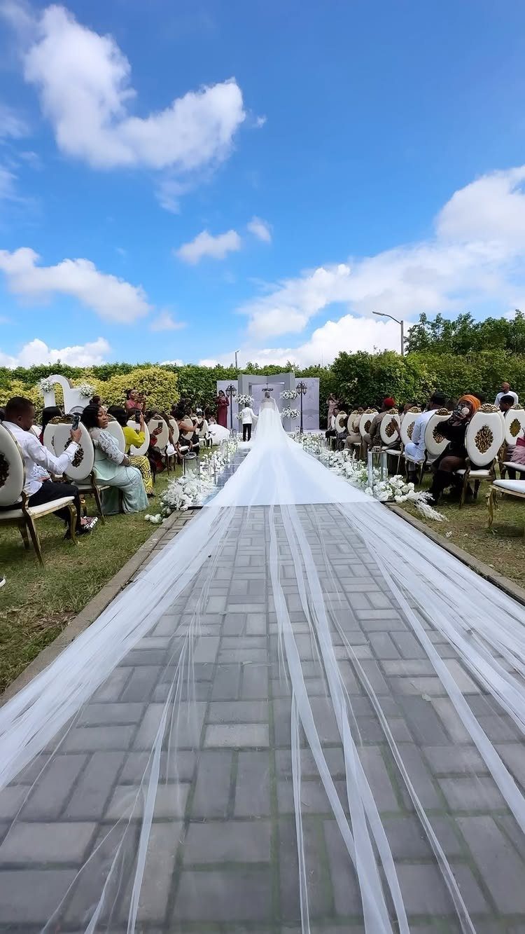 White tulle aisle runner leading to a floral altar at an outdoor ceremony.