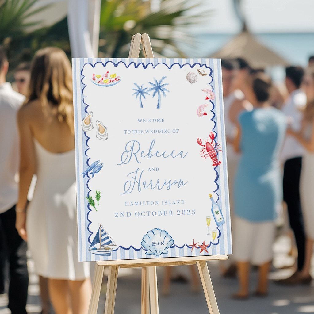 Wedding welcome sign with nautical illustrations on a wooden easel at a beach.