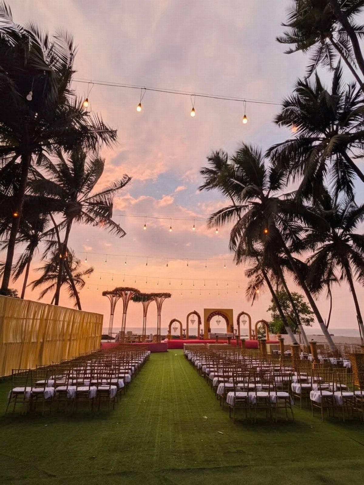 Outdoor wedding ceremony setup with white chairs and altar on a beachy lawn.