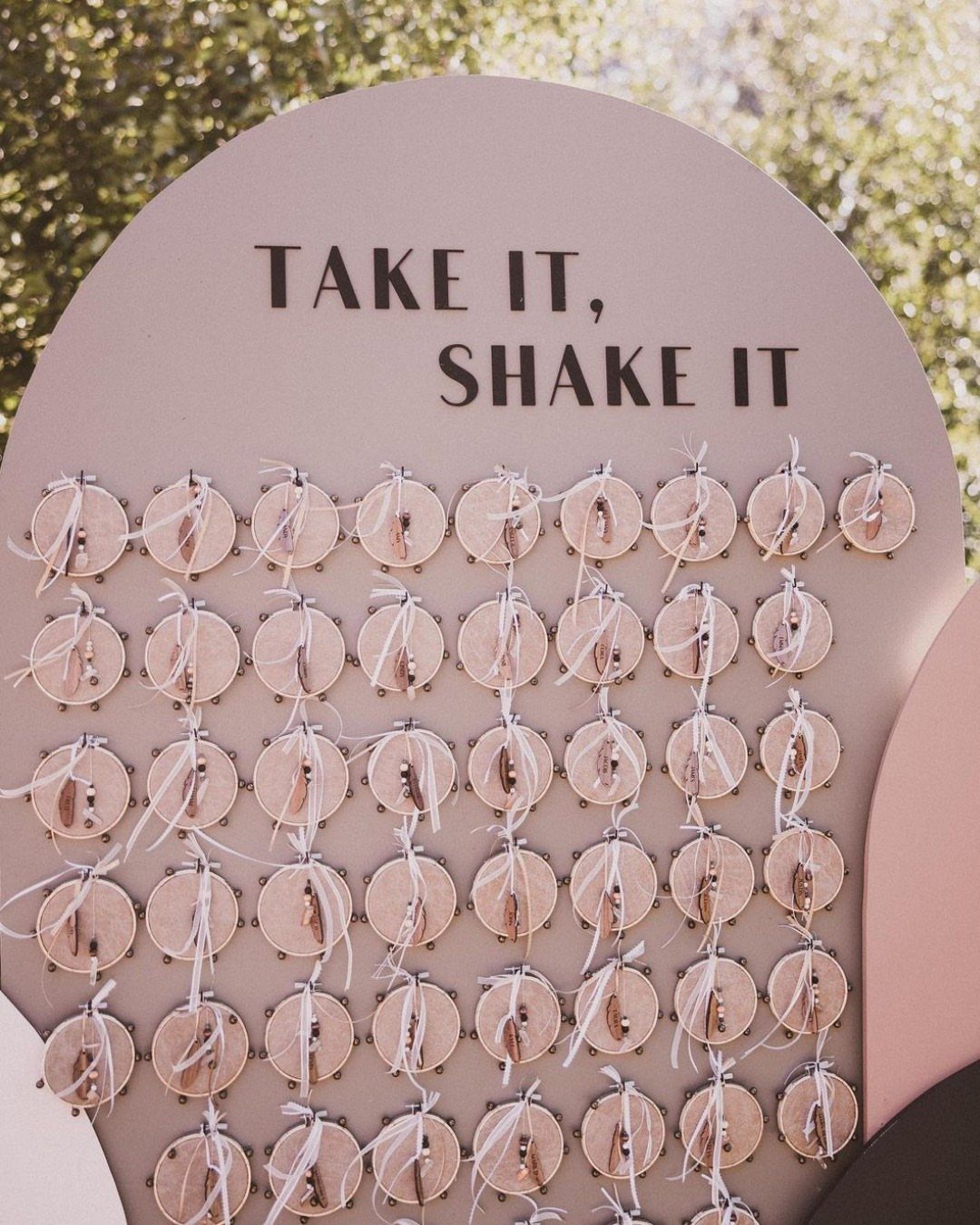 Pink arched board with small wooden tambourines for guests to shake during ceremony.