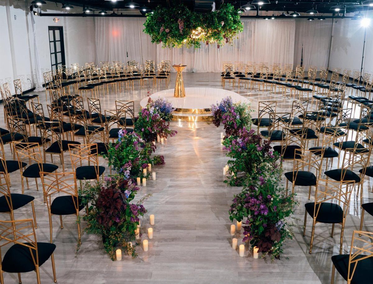 Gold chairs and floral arrangements arranged for a wedding ceremony in a hall