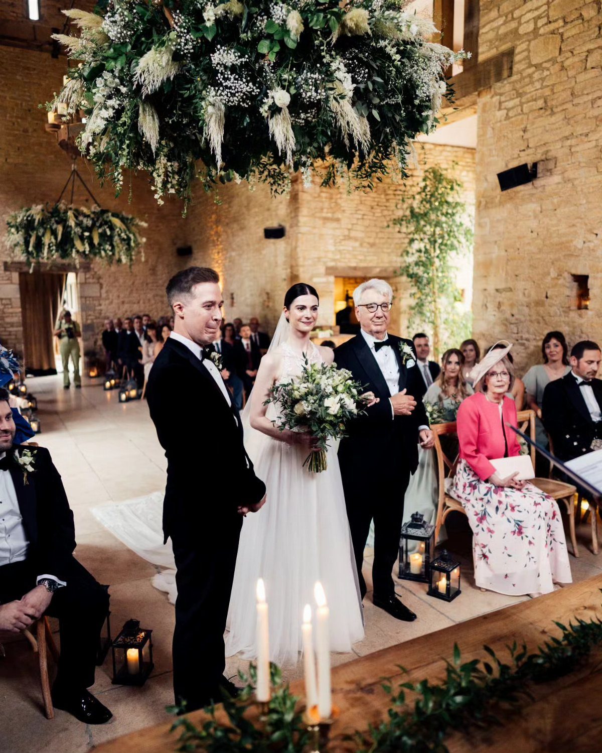 Bride and groom standing at the altar inside a rustic stone barn venue.