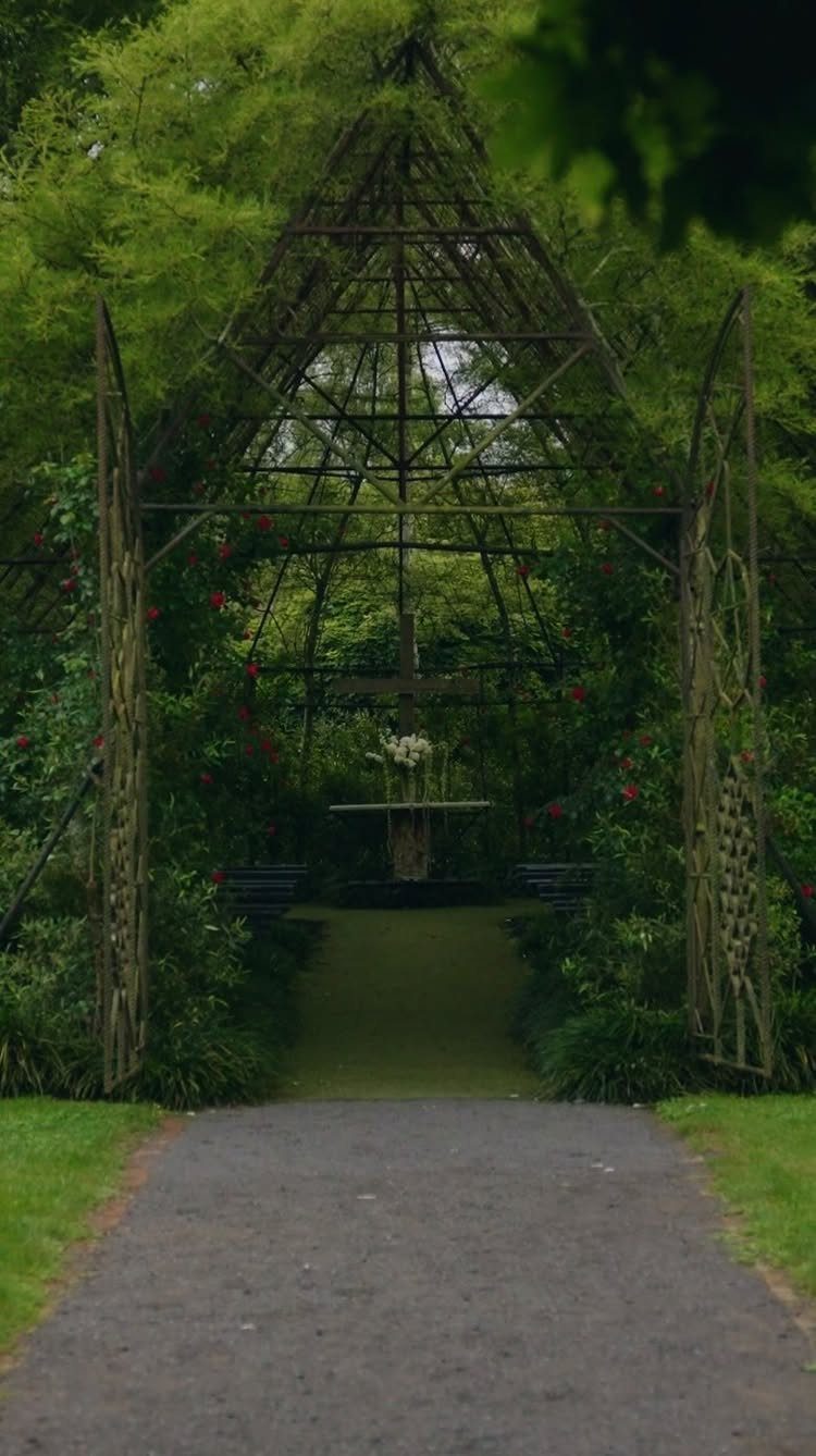 Metal garden trellis covered in greenery with a wedding altar inside