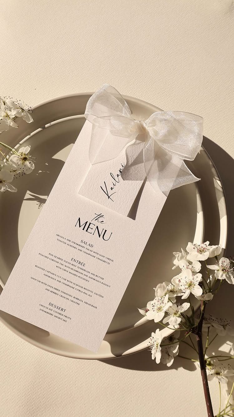Wedding menu card with a white bow on a beige plate with blossoms