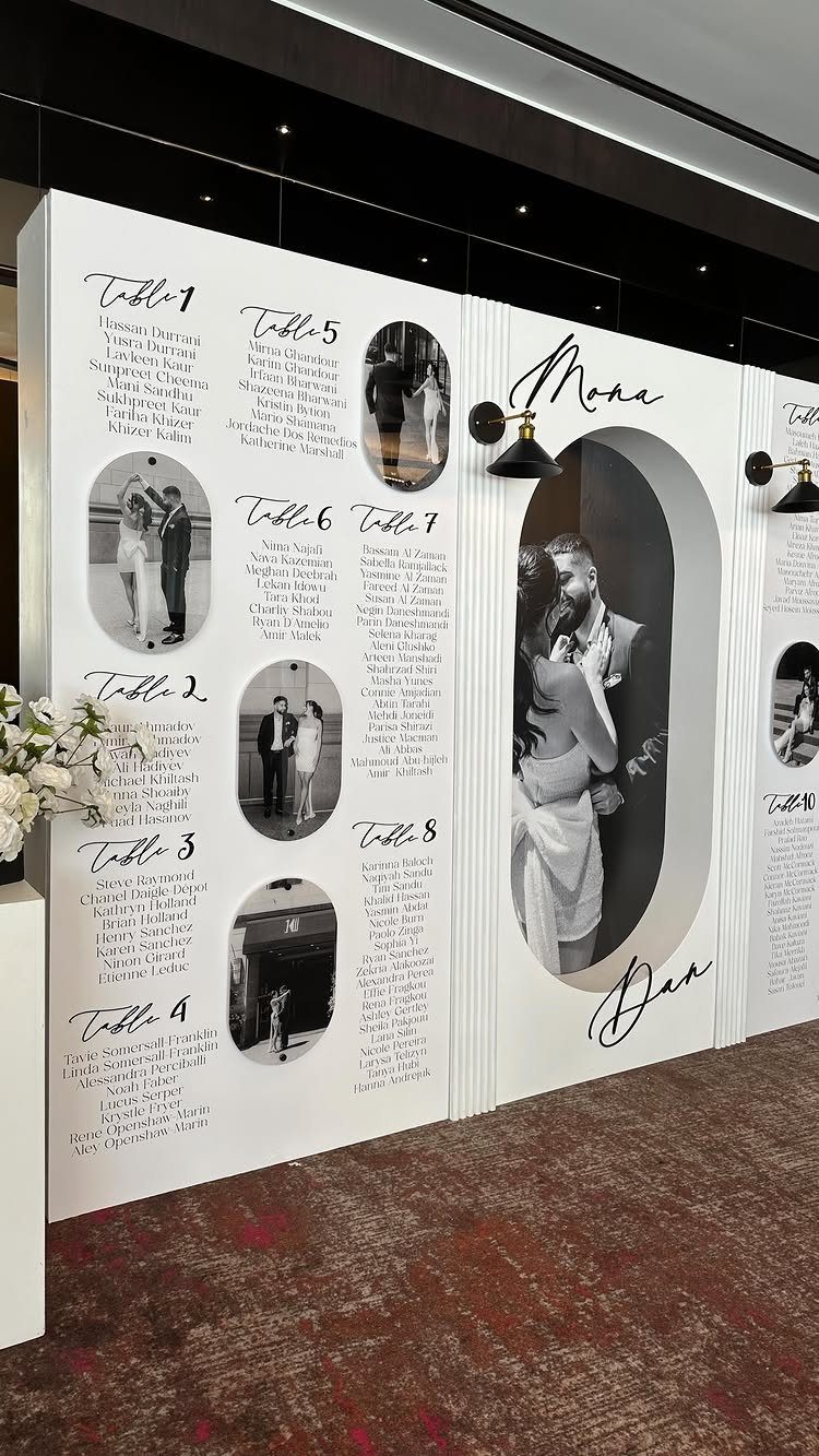 Wedding reception seating chart board with table lists and black and white couple photos.