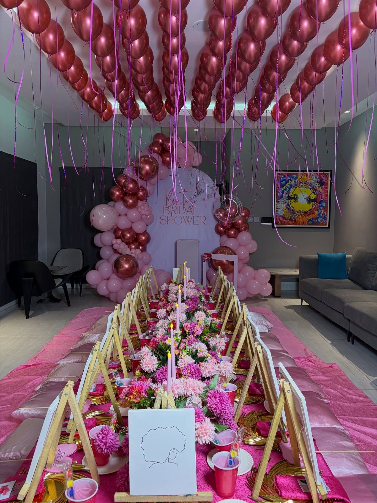Long dining table decorated with pink flowers and balloons for a bridal shower.